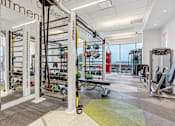 Thumbnail 20 of 26 - A gym with a variety of equipment including a pull up bar, weights and a bench.