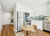 Thumbnail 12 of 26 - A modern kitchen with a table and chairs.