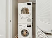 Thumbnail 14 of 26 - A white washing machine and dryer in a small laundry room.