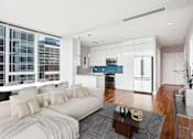 Thumbnail 9 of 26 - A modern living room with a white sofa and a glass table.