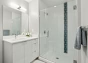 Thumbnail 13 of 26 - A white bathroom with a glass shower door and a white sink.