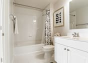 Thumbnail 6 of 25 - A white bathroom with a toilet, sink, and shower.