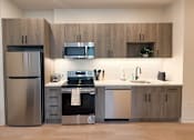 Thumbnail 16 of 20 - A modern kitchen with a stainless steel refrigerator and a black oven.at The Jones Tower at the Collective, Pittsburgh, PA 15203