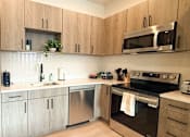 Thumbnail 10 of 20 - A kitchen with wooden cabinets and stainless steel appliances.at The Jones Tower at the Collective, Pittsburgh, PA 15203