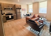 Thumbnail 1 of 20 - A modern kitchen and living room with a brown leather couch and a wooden floor.at The Jones Tower at the Collective, Pittsburgh, PA 15203