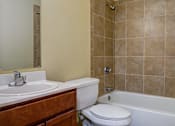 Thumbnail 11 of 25 - A bathroom with a white toilet, a sink, and a bathtub.