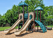 Thumbnail 17 of 25 - A playground with a green slide and brown slide.