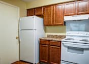 Thumbnail 14 of 25 - A white refrigerator stands next to a stove in a kitchen.