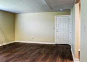 Thumbnail 2 of 25 - A room with a white door and wooden floors.