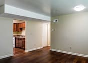 Thumbnail 5 of 25 - A room with a kitchen in the background and a doorway leading to another room.