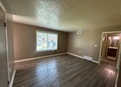 Thumbnail 3 of 17 - A room with a window and wooden flooring.