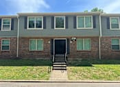 Thumbnail 16 of 17 - A brick building with a black door and windows with white frames.