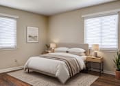Thumbnail 6 of 25 - A bedroom with a large bed and a small table with a lamp on it.