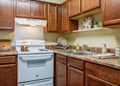 Thumbnail 12 of 25 - A kitchen with brown cabinets and a white stove.