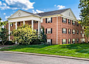 Thumbnail 2 of 15 - A red brick building with a white roof and columns.