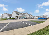 Thumbnail 37 of 40 - A parking lot in front of a row of houses with cars parked.