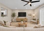 Thumbnail 11 of 40 - A living room with a white couch, a wooden coffee table, a flat screen TV, and a ceiling fan.