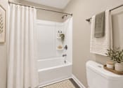 Thumbnail 20 of 40 - A white bathroom with a shower curtain and a towel hanging on the towel rack.