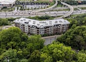 Thumbnail 59 of 64 - A large building with a green roof is surrounded by trees.