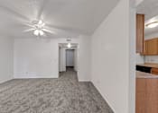 Thumbnail 10 of 27 - A spacious room with a ceiling fan and carpeted floor.
