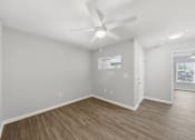 Thumbnail 12 of 27 - A room with a ceiling fan and wooden flooring.