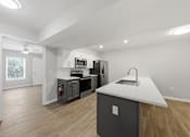 Thumbnail 1 of 27 - A kitchen with a white countertop and wooden flooring.