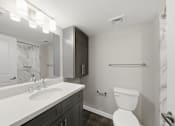 Thumbnail 19 of 27 - A white toilet sits in a bathroom next to a sink and a mirror.