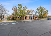 Thumbnail 38 of 57 - an empty parking lot in front of a brick building with a car parked in front at Indian Lookout Apartments, Ohio