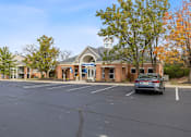 Thumbnail 36 of 57 - an empty parking lot in front of a brick building with a car parked in front at Indian Lookout Apartments, West Carrollton, OH, 45449