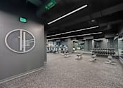 Thumbnail 44 of 49 - A gym with a green exit sign and a clock on the wall at Sky Central Apartments, Cincinnati