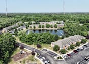 Thumbnail 21 of 21 - A bird's eye view of a parking lot with a lake and buildings in the background.
