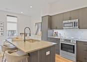 Thumbnail 15 of 81 - Kitchen with gray cabinets and a large island with a sink and two stools at Four23/Hoge, Cincinnati, OH