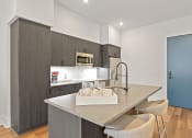 Thumbnail 16 of 81 - Kitchen with gray cabinets and a large island with a sink and two stools at Four23/Hoge, Ohio, 45226