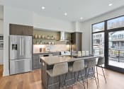 Thumbnail 9 of 81 - Kitchen with stainless steel appliances and a large island with four chairs at Four23/Hoge, Cincinnati