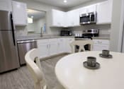 Thumbnail 3 of 40 - A white kitchen with a table and chairs.
