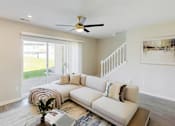 Thumbnail 8 of 40 - A living room with a white couch and a ceiling fan.