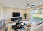 Thumbnail 10 of 40 - A modern living room with a flat screen TV, a coffee table, and a ceiling fan.