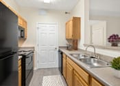 Thumbnail 18 of 54 - A kitchen with a black refrigerator and wooden cabinets.