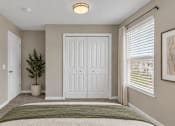Thumbnail 15 of 40 - A bedroom with a bed, a plant, and a framed picture on the wall.