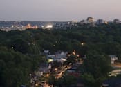 Thumbnail 25 of 25 - A cityscape at dusk with buildings and trees in the foreground.