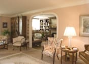 Thumbnail 7 of 25 - A living room with a chair, a table, and a lamp.