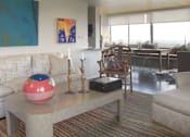Thumbnail 5 of 25 - A living room with a couch, a table, and a painting on the wall.