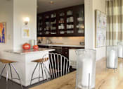 Thumbnail 2 of 25 - A kitchen with a white counter and brown chairs.