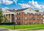 Thumbnail 4 of 15 - A large red brick building with a white trim and a black lamp post in front.