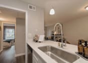Thumbnail 16 of 33 - A kitchen with a white countertop and a stainless steel sink at A62 Apartments, Indianapolis 46220