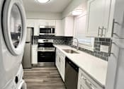 Thumbnail 1 of 33 - A modern kitchen with white cabinets and a black backsplash at A62 Apartments, Indianapolis 46220