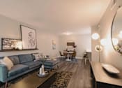 Thumbnail 11 of 33 - A modern living room with a grey sofa, a coffee table, and a round mirror on the wall at A62 Apartments, Indianapolis