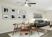 Thumbnail 5 of 33 - A living room with a grey couch, a wooden table and chairs, a rug, and a ceiling fan at A62 Apartments, Indianapolis