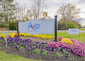Thumbnail 33 of 33 - A sign for A/62 Apartments is surrounded by flowers at A62 Apartments, Indianapolis, IN 46220