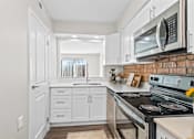 Thumbnail 1 of 32 - A kitchen with white cabinets and a brick backsplash.